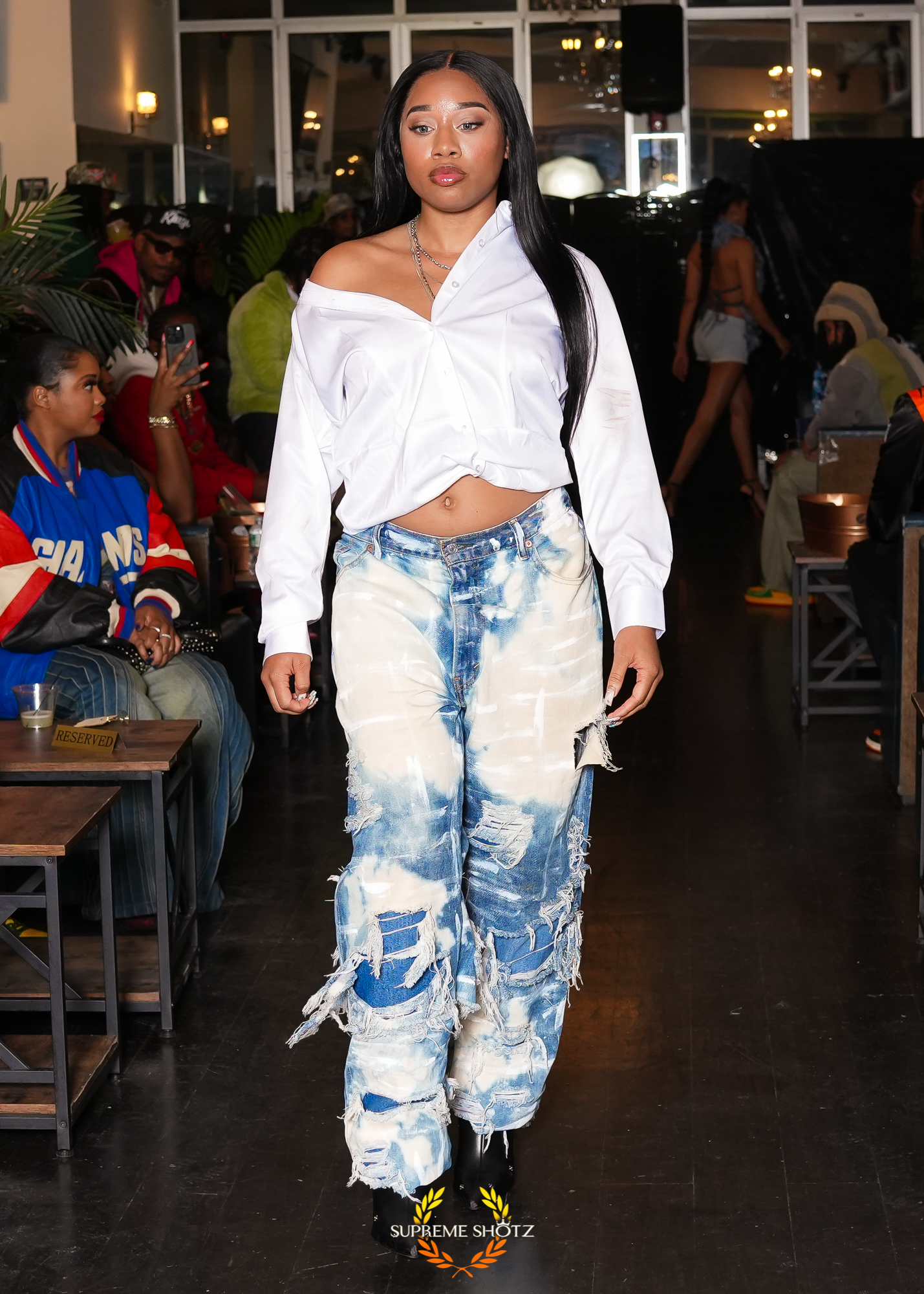 Taniya posing at the end of the runway in bleached distressed denim and black boots