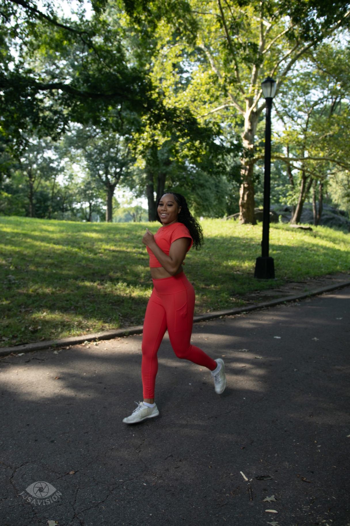 Taniya running along a park path in a red activewear set, smiling