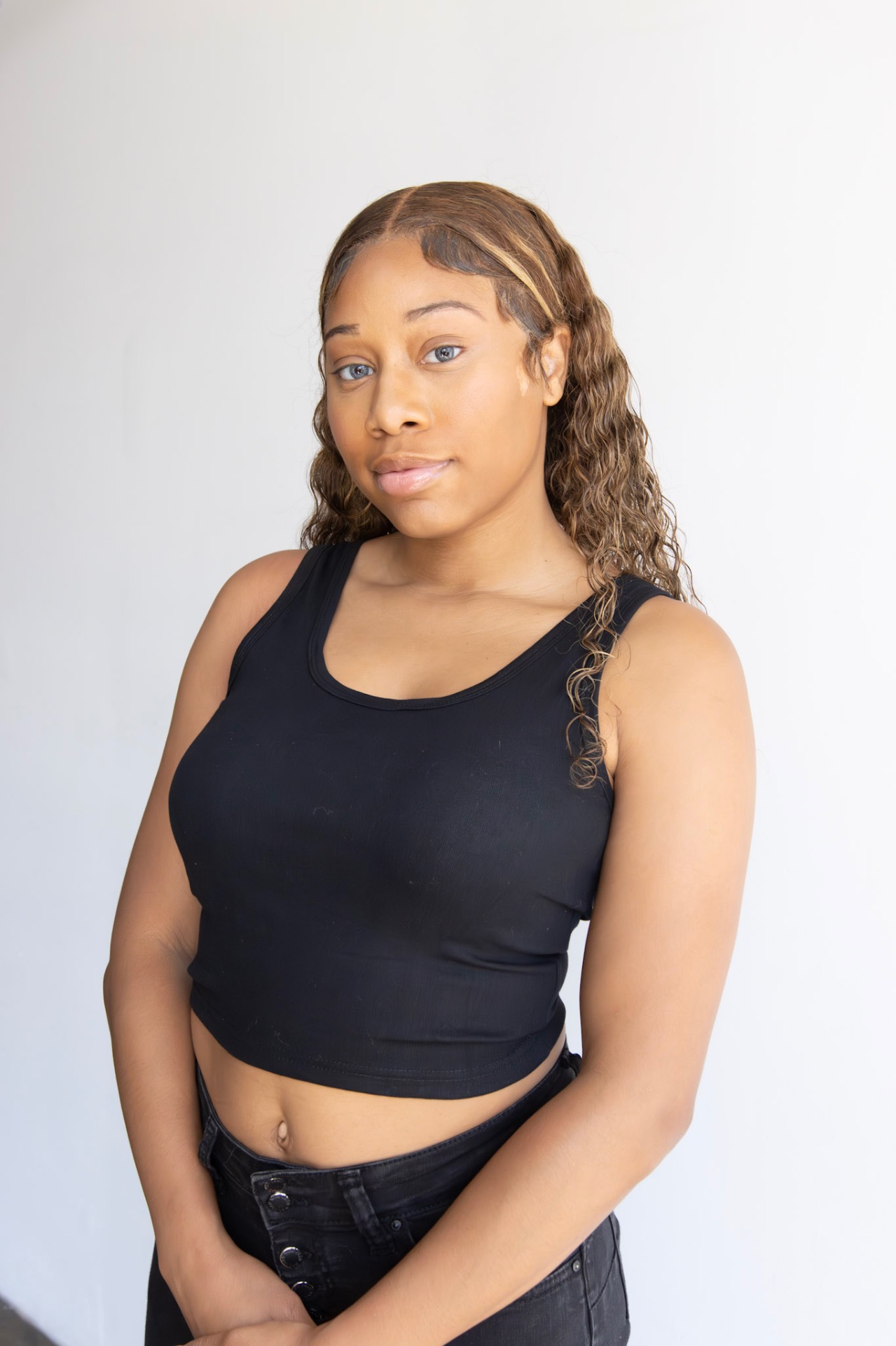 Waist-up agency digital of Taniya in a black tank, natural hair and no makeup