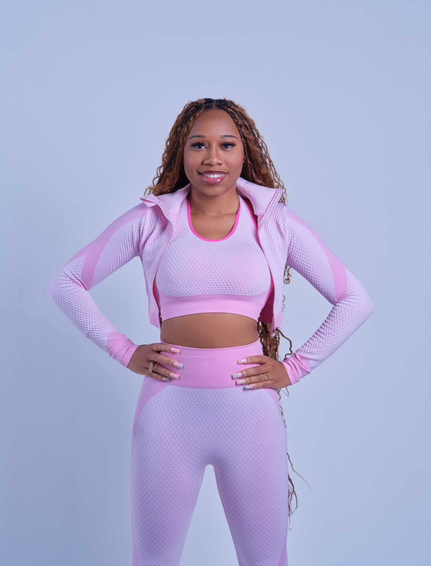Taniya smiling in a pink activewear set with hands on hips