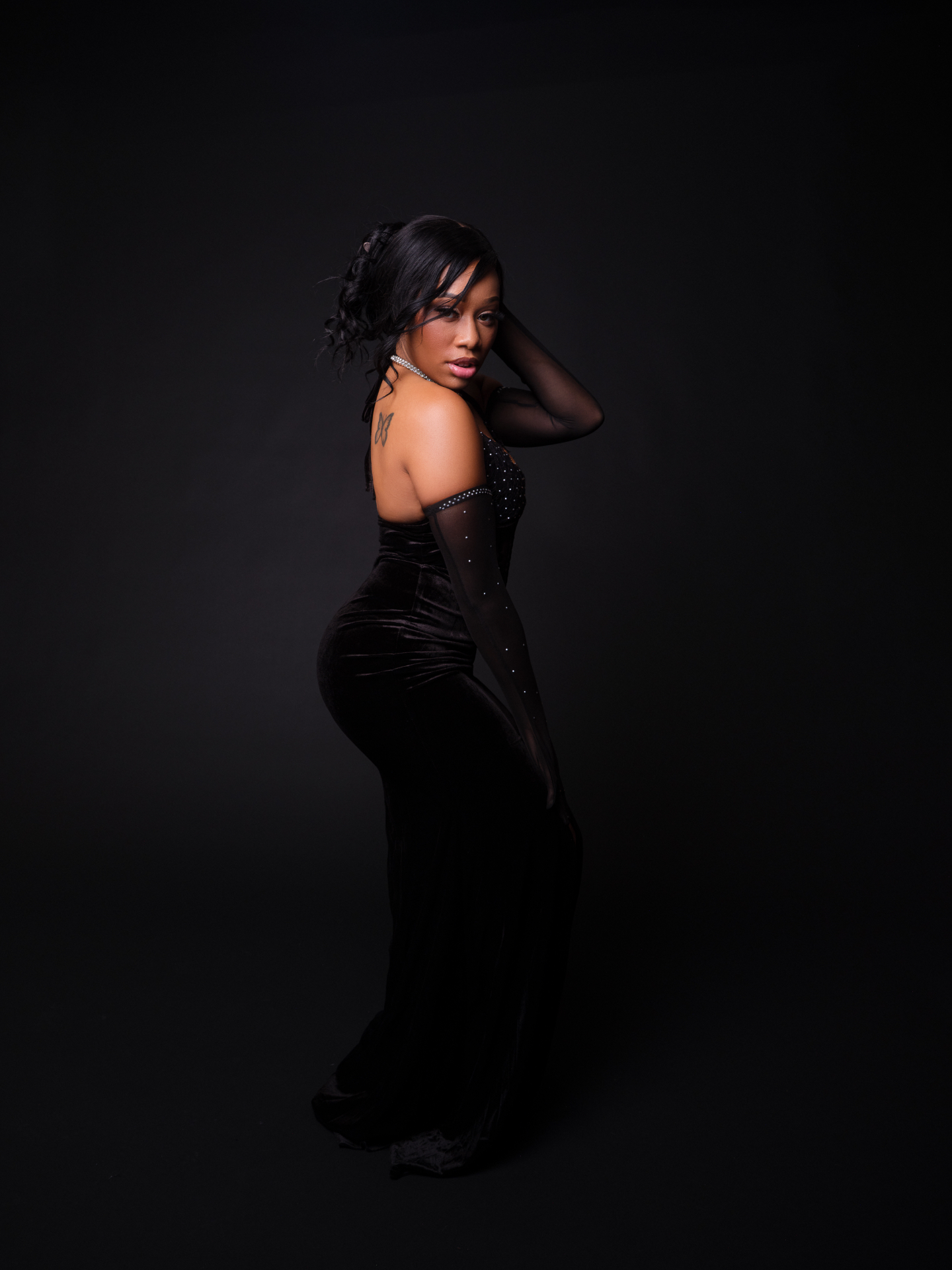 Taniya looking over her shoulder in a fitted black velvet evening gown