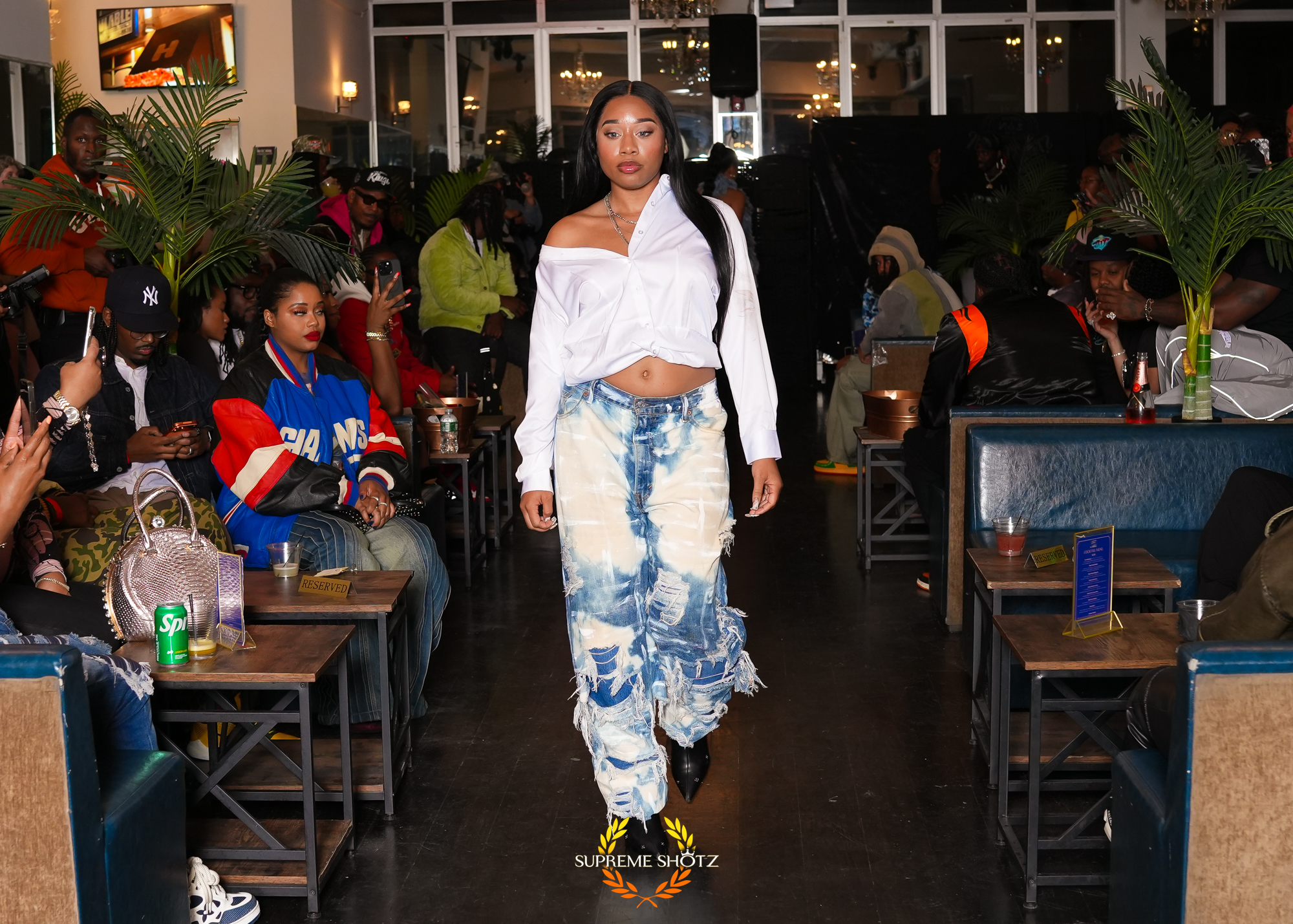 Taniya walking the runway in an off-shoulder white shirt and bleached distressed denim